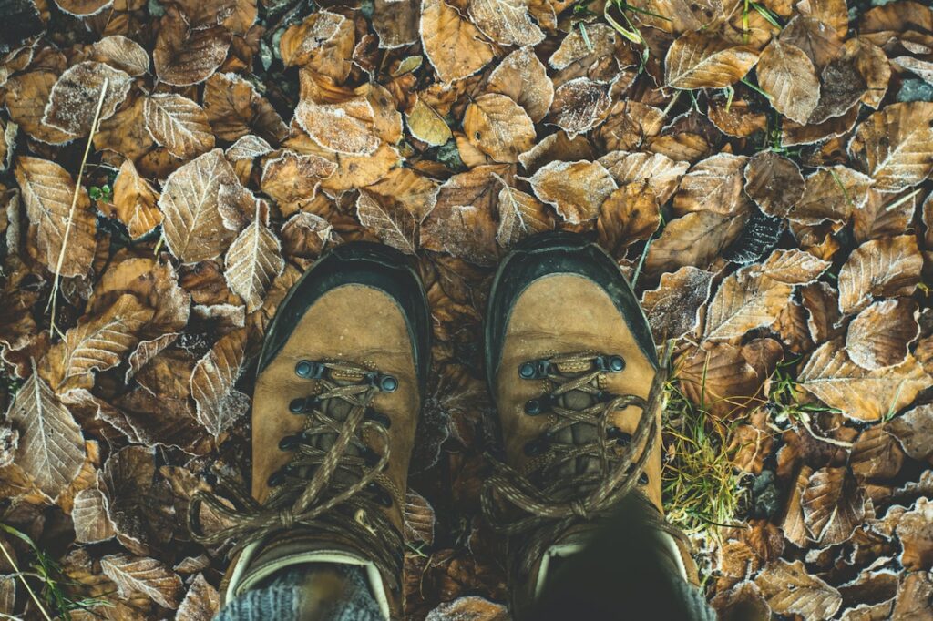 Person wearing hiking boots standing on a pile of dried leaves