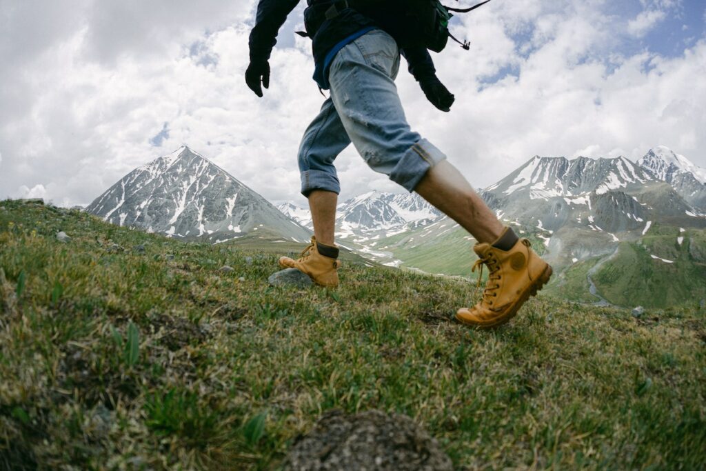 Man walking up a hill wearing a pair of brown hiking boots