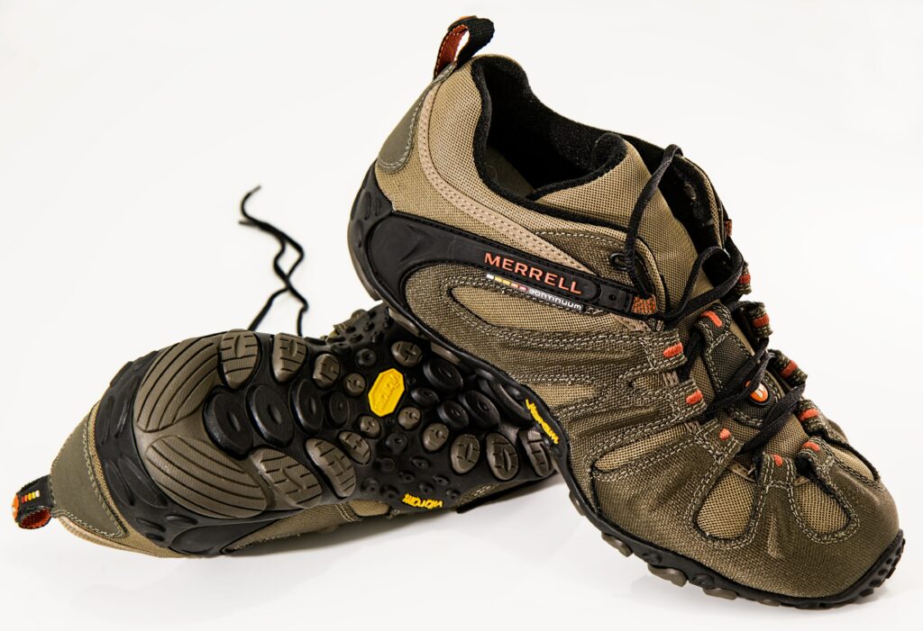 A pair of brown hiking shoes for outdoor activities atop one another.